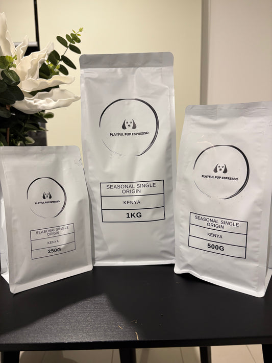 Three coffee bags with 'Playful Pup Espresso' branding on a dark surface.