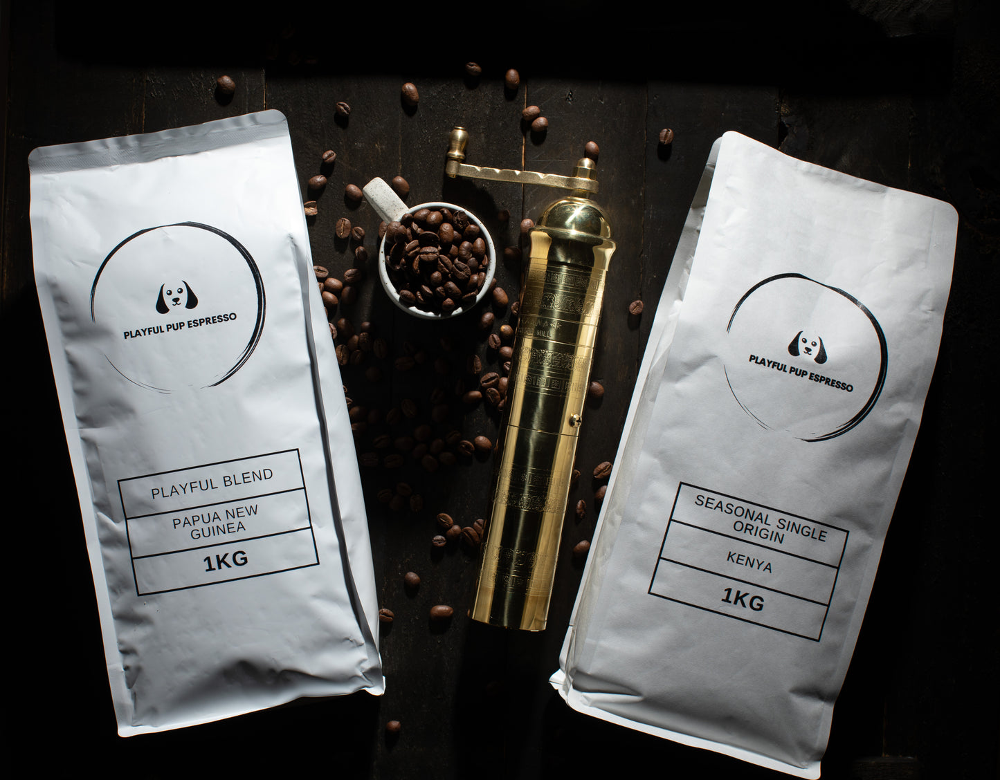 Two coffee bags labeled 'Playful Blend' and 'Seasonal Single Origin Kenya' with coffee beans and a gold container on a dark surface.